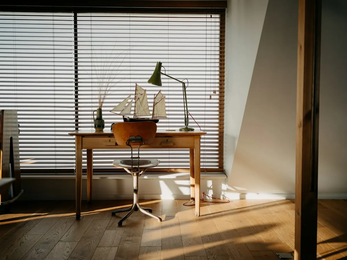 Schreibtisch am Fenster mit Schiffsmodell und Lampe im Abendlicht